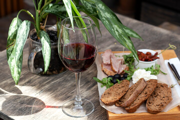 Wine and snack set. Flat-lay of wineglasses and cheese and appetizers board over concrete background, top view. Party food concept, cafe.