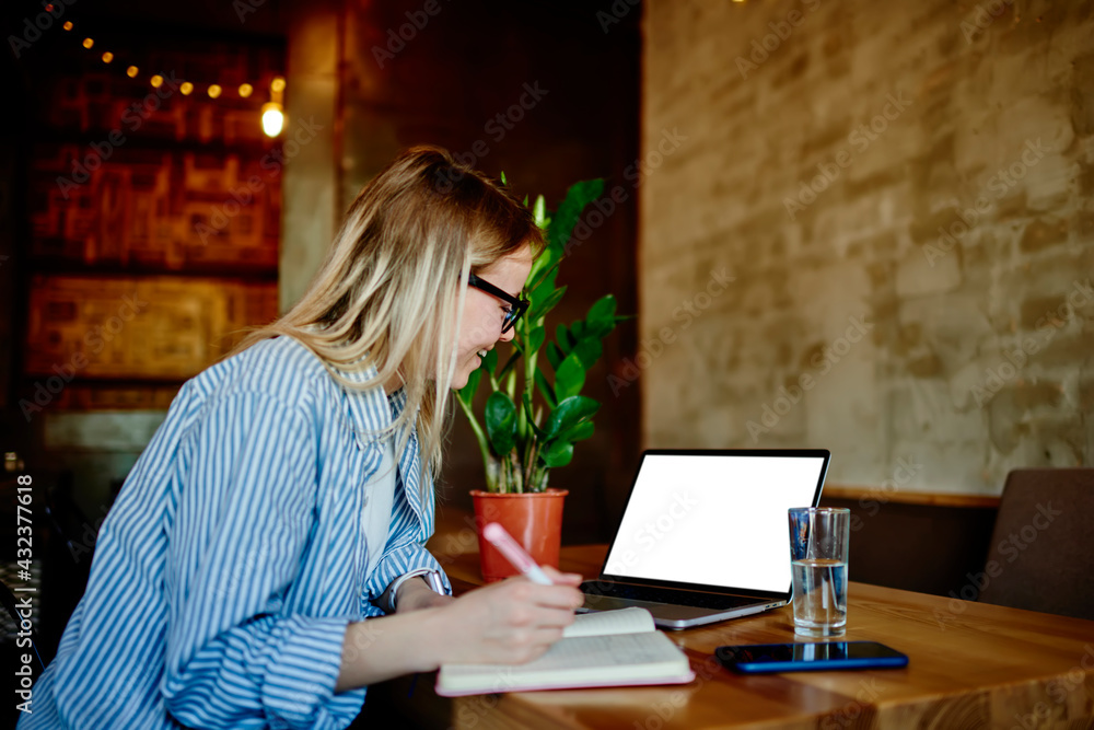 Poster cheerful female student watching education webinar for making informative notes in textbook enjoying