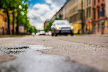 Sunny day after rain in the city, the car rides along the road. Close up view from the asphalt level