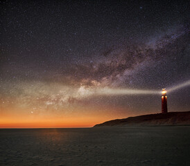 Night image of the Texel lighthouse serving as a navigation beacon for ships with starry nightsky with Milky way galactic core - obrazy, fototapety, plakaty