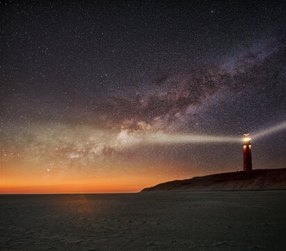 Night image of the Texel lighthouse serving as a navigation beacon for ships with starry nightsky with Milky way galactic core