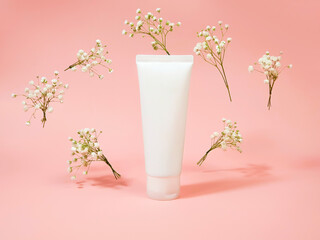 Top view of mockup white squeeze bottle plastic tube and flying gypsophila flowers at light pink...