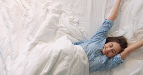 Top view of the pleasant blonde girl started her morning at the bed. Girl wearing pajama stretching and yawns while laying at the white bed and feeling happy at the weekend. Stock video