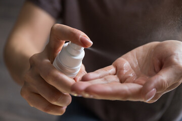 Close up view of woman person using small portable antibacterial hand sanitizer on hands. Coronavirus epidemic prevention concept.