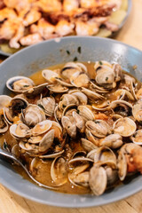Clams cooked in sauce served in a deep plate.