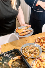 Woman serving shrimp and different seafood with tongs.