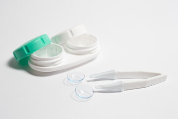 Contact lenses, tweezers and lens storage container on the table