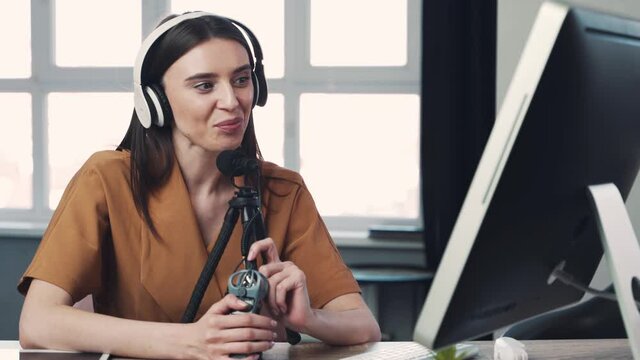Woman blogger or vlogger streaming online on social media to her subscribers. Woman using microphone and computer for video calll
