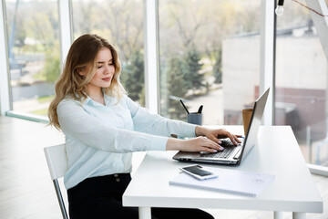 Young beautiful businesswoman works in the office with a laptop. Success