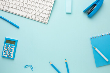 Working blue table with a keyboard, calculator, notebook, eraser, pencil, felt-tip pen, stapler and...