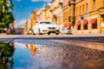 Sunny day after rain in the city, the headlights of the approaching car on the road. Close up view...
