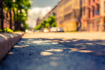 Sunny day after rain in the city, the empty road lit by the sun. Close up view from the curb level