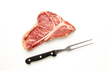 Raw beef steak on the bone with a fork on a white background. Top view with copy space