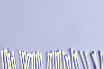 Cotton sticks border, frame on textured purple background. Top view, copy space, line
