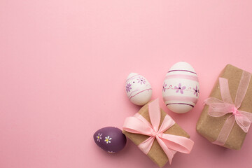 Easter greeting card with colorful easter eggs and a present on pink background. Top view flat lay with space for your greetings