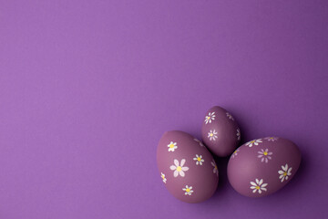Easter greeting card with colorful easter eggs on purple background. Top view flat lay with space...