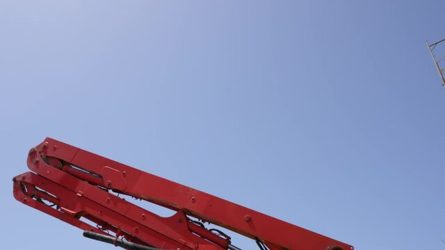 View of the hydraulic arm of a concrete pump rising against the sky.