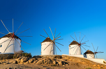 Famous tourist attraction of Mykonos, Cyclades, Greece. Four traditional whitewashed windmills by waterfront. Summer, travel destination, iconic view.