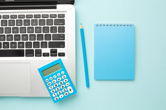 Office blue desk table with laptop computer, notebook, pencil, calculator. Top view with copy space