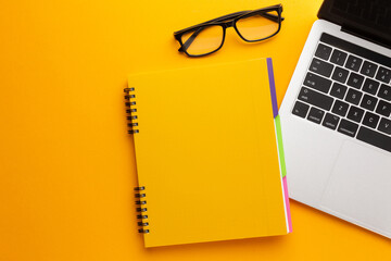 Notebook with notepad and pencil on a yellow work table.