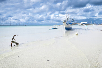 boat on the tropical Caribbean beach and stormy cumulus clouds in the background