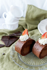Chocolate Swiss Roll Cake with Chocolate cream filling and Strawberry set on cafe table.