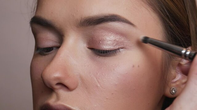 The makeup artist applies bronze shadows on the female eye