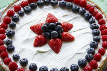 fresh fruits cake decorated with berries and whipped cream