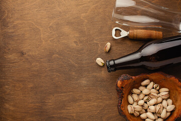 A bottle of beer on a plate with salted ookies pretzels, pistachio nuts and chips on a black...