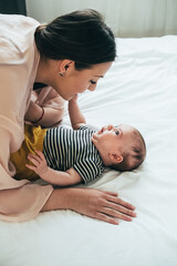 Happy Mother Playing with her Cute Baby at Home.
Loving mother playing with newborn baby boy,...