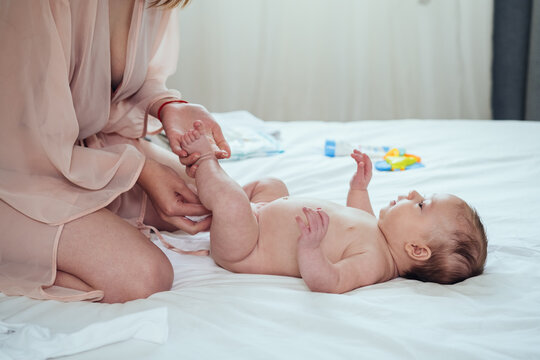 Newborn Baby Getting a Diaper Change at Home .
Close up photo of mom hands wiping baby's bottom with baby wipe in bed. 