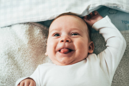 Close Up Photo of Adorable Baby Sticking Out his Tongue
Face of curious newborn baby boy looking at the camera with with tongue sticking out while lying in bed at home.