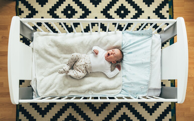 Top View of Cute Baby Sleeping and Yawning in his Crib at Home.
Portrait of a little baby boy...
