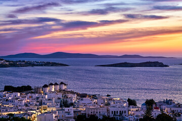 Colorful sunset view famous traditional white windmills, Mykonos, Greece. Whitewashed houses, colorful sunset sky, summer destination, town lights on