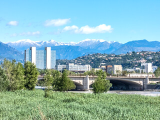 Fototapeta premium Bâtiment de la Préfecture des Alpes Maritimes et pont Alexandre III à Nice au pied des sommets enneigés du Mercantour dans le Sud de la France sur la Côte d'Azur
