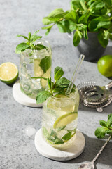 Two mojito with lime, mint, and ice cube on gray background. Close up.