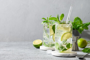 Two mojito with lime, mint, and ice cube on gray background. Copy space.
