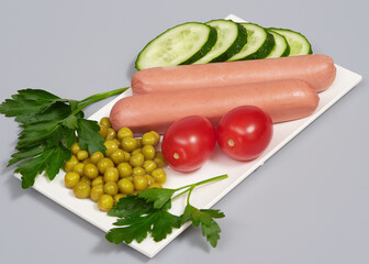 Snack with sausages, cucumber, tomatos and canned peas on gray background, isolated