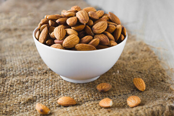 Almond nuts in a white bowl wooden background, selective focus.front view.close-up.