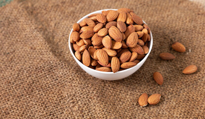 Almond nuts in a white bowl on wooden background, top view, flat lay, top-down, selective focus.copy space.