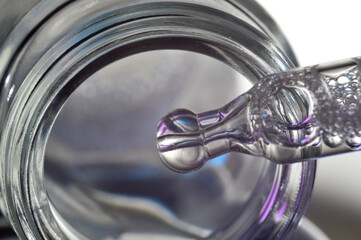 a cosmetic pipette filled with a bubbling liquid and a bottle. close-up.