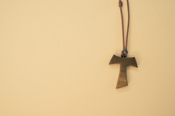 Closeup shot of a wooden tau cross necklace isolated on a brown background