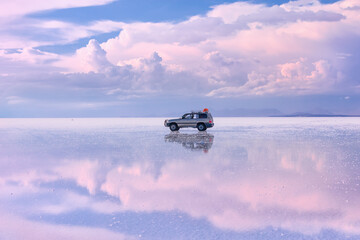 off-road vehicle stands on the salt flat of Uyunu at sunset - Altiplano, Bolivia, South America....