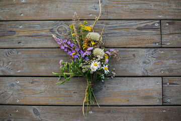 Beautiful bouquet of wildflowers on rustic wood background. Summer vacation in countryside. Top view