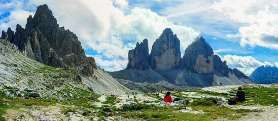 Fototapeta premium Tre Cime di Lavaredo peaks on a summer day with relaxed hikers after the walk, Sudtirol, Drei Zinnen, Trentino Alto Adige, Italy
