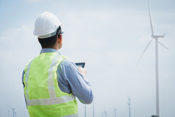 Engineer windmills using tablet with wind turbine in background