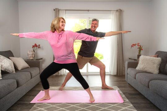 Older Middle Aged Couple Stretching And Exercising At Home Together, Cheerful, Bonding And Having Fun With A Healthy Living Lifestyle