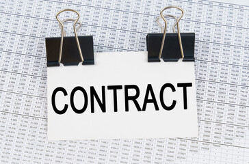 On the table there are reports and a business card with the inscription - CONTRACT