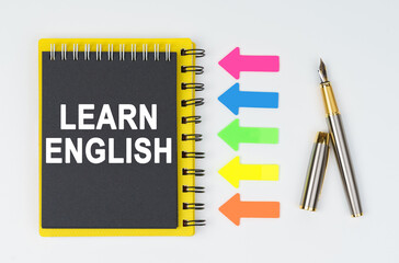 On a white background lies a pen, arrows and a notebook with the inscription - LEARN ENGLISH