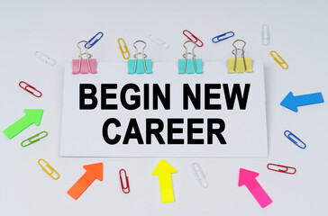 On the table there are paper clips and directional arrows, a sign that says - Begin New Career